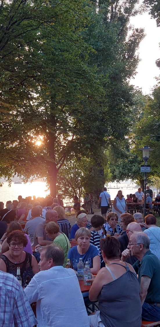 Veranstaltungsfoto. Abgebildet ist das Publikum auf Bierbänken. Im Hintergrund ist der Bodensee.